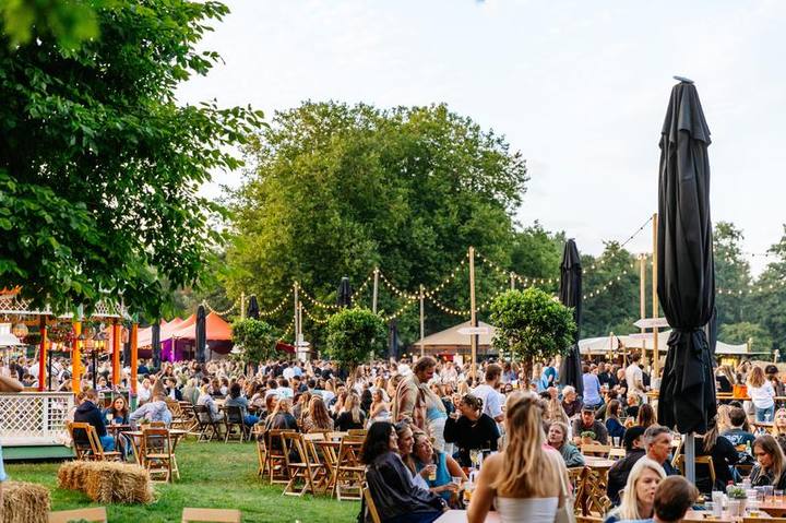 Mensen ontspannen op een zomerse tuinlocatie met slingers en lampions